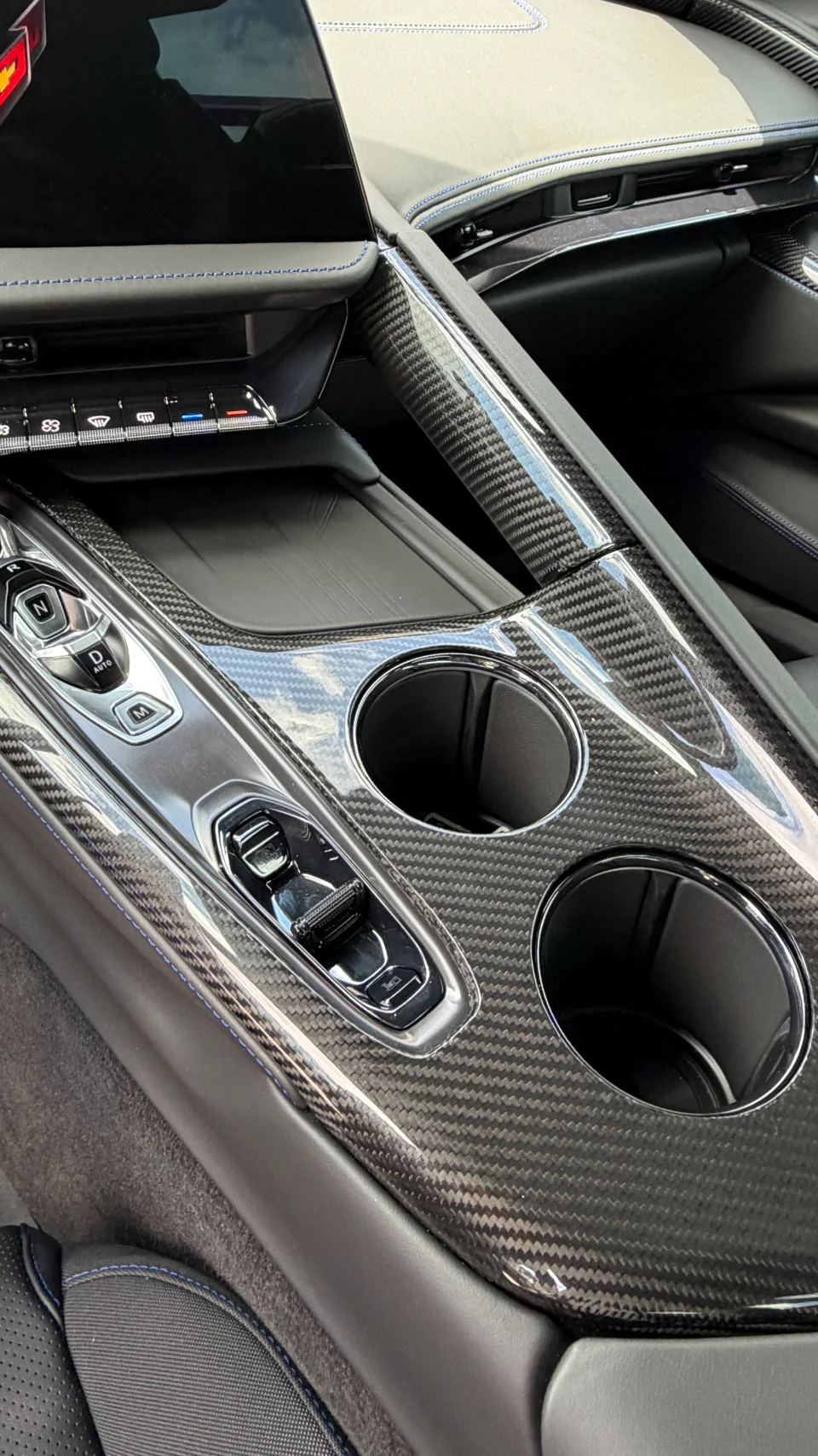 Close-up of a C8 Corvette interior featuring carbon fiber trim on the center console, cup holders, and gear selector.