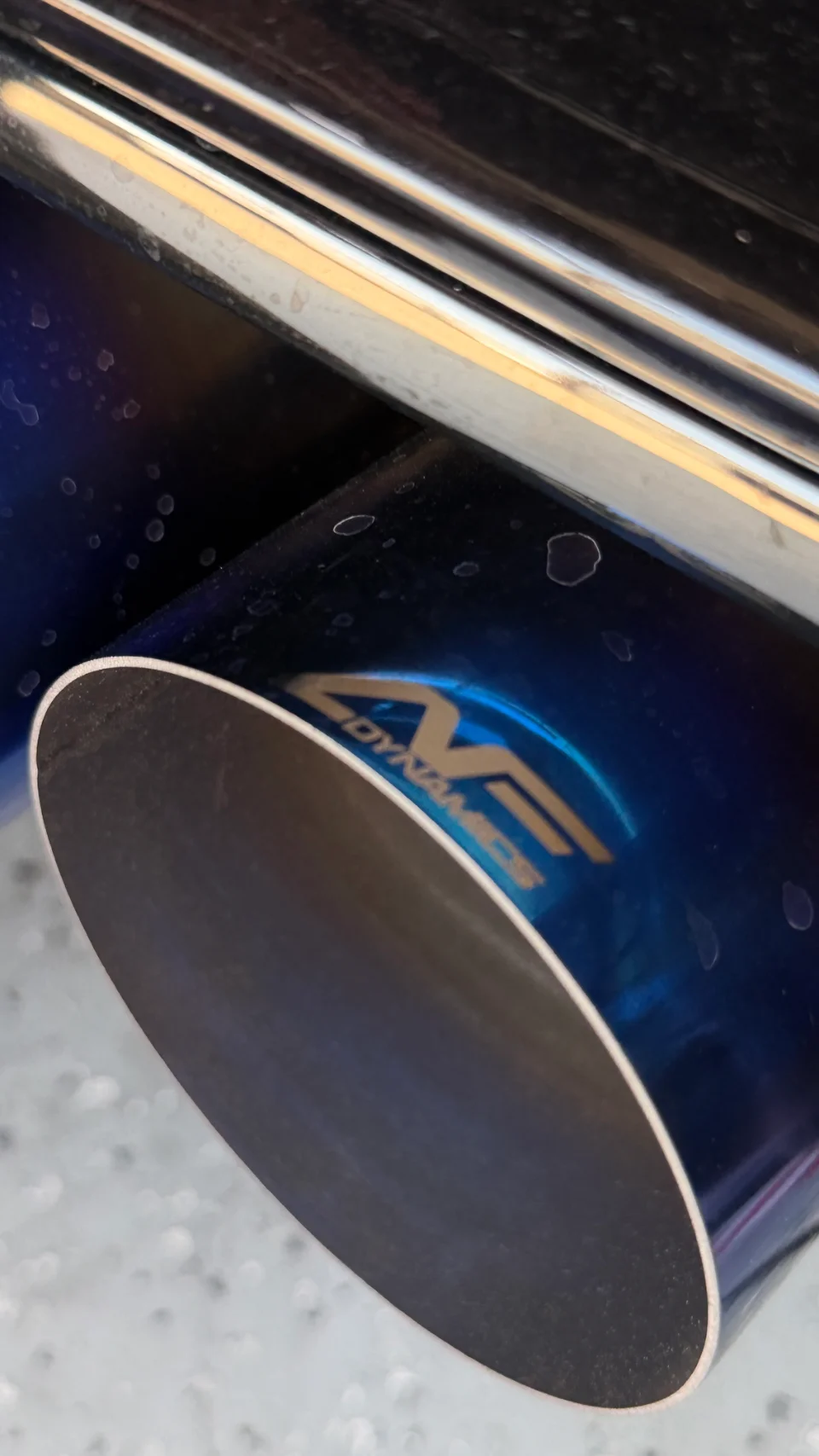 A close-up detail shot of a blue aFe Dynamics exhaust tip on a performance car.