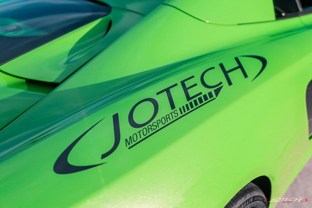 Close-up of a bright green McLaren with Jotech Motorsports branding on the rear fender, showcasing the car's vibrant finish.