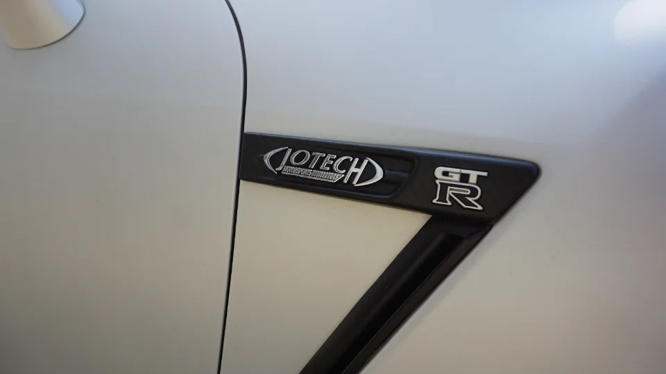 Close-up of a white Nissan GT-R fender with Jotech Motorsports and GT-R emblems.