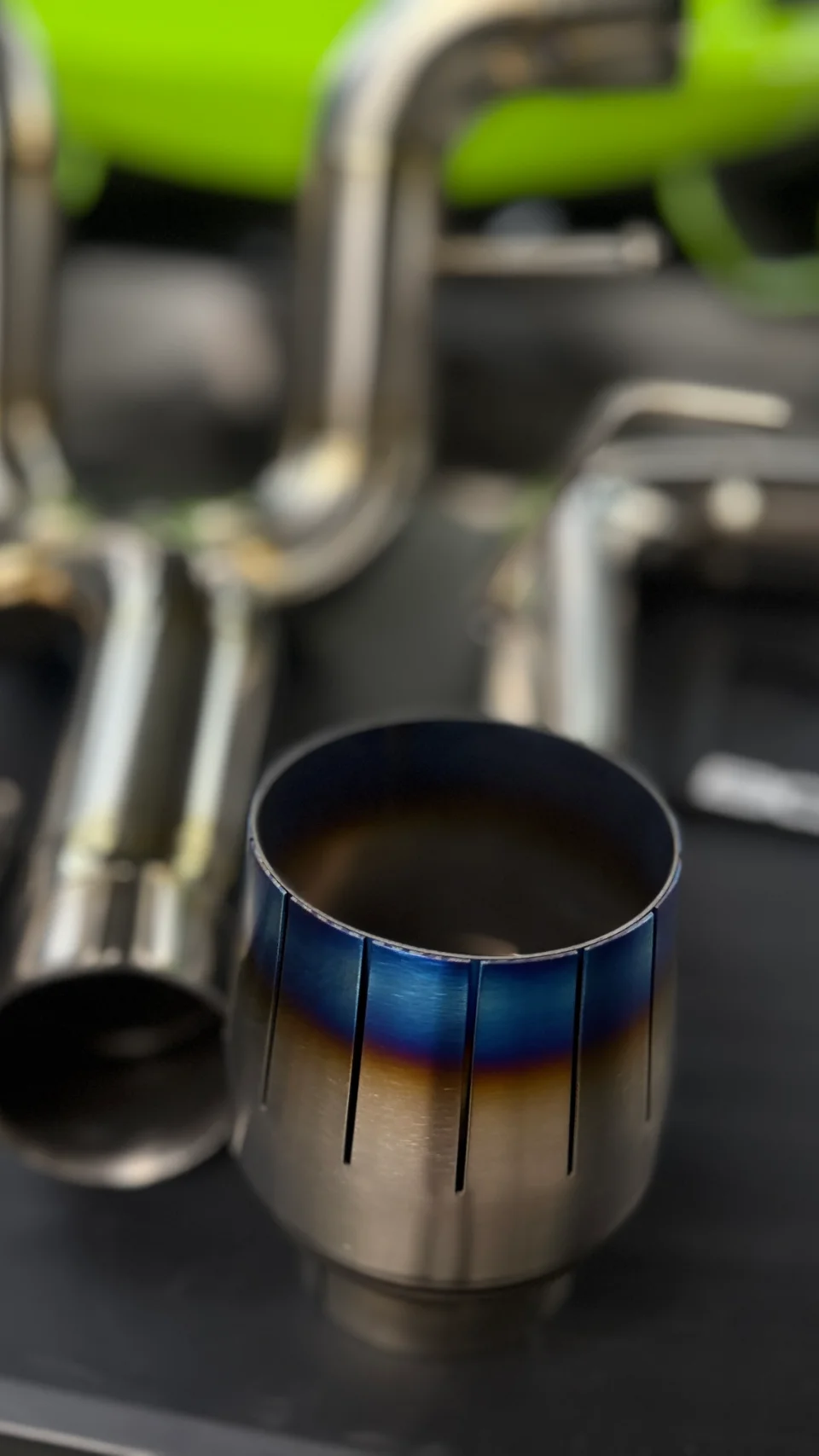 Close-up of a titanium exhaust tip with a blue and gold heat-discolored finish, part of a performance exhaust system.