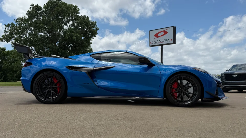 A blue Chevrolet Corvette C8 Z06 with an aftermarket wing and splitter parked outside Jotech Motorsports.