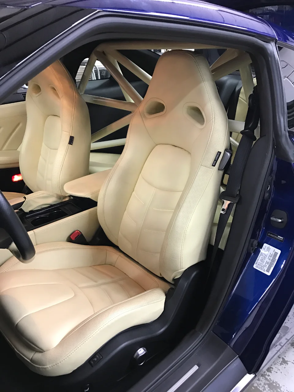 Custom cream leather interior with racing seats and a roll cage in a blue Nissan GT-R.