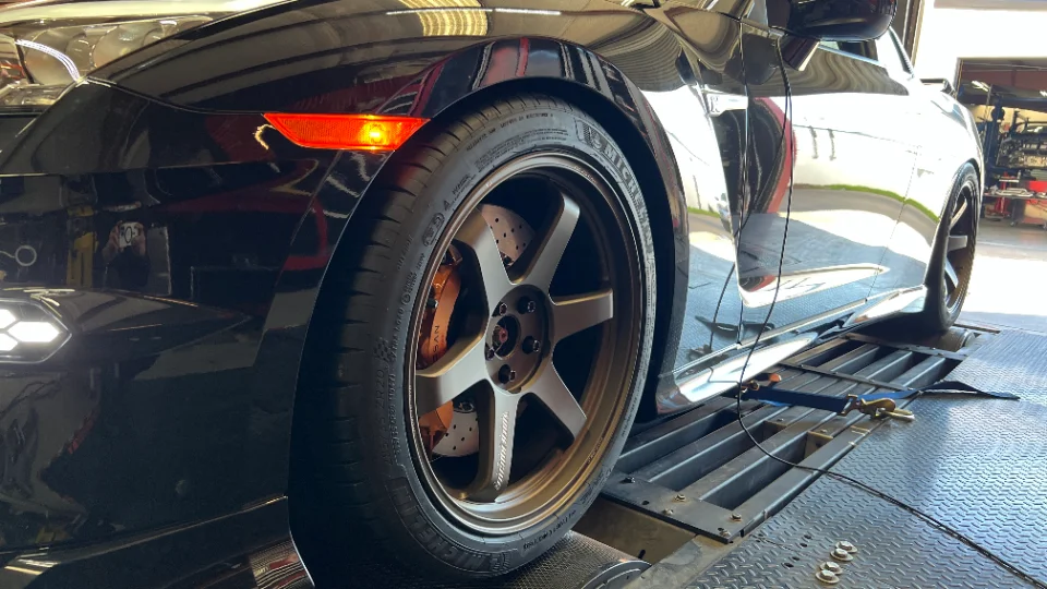 A black Nissan GT-R on a dyno, showcasing bronze Volk TE37 wheels, Michelin tires, and drilled brake rotors.