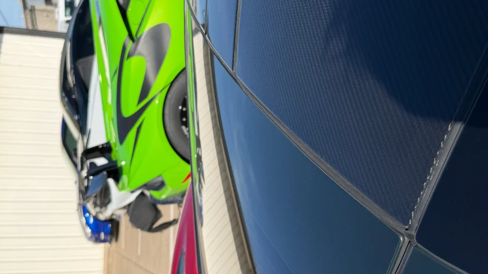 A close-up detail shot of a bright green motorcycle's body panel next to a dark carbon fiber surface.