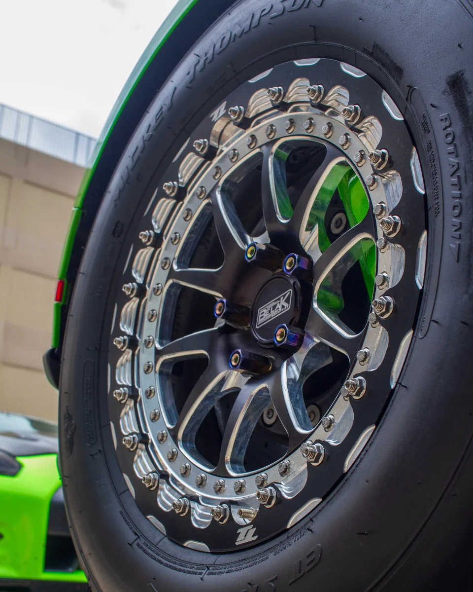 Close-up of a green car's drag wheel with a Mickey Thompson tire and Belak Industries beadlock wheel.