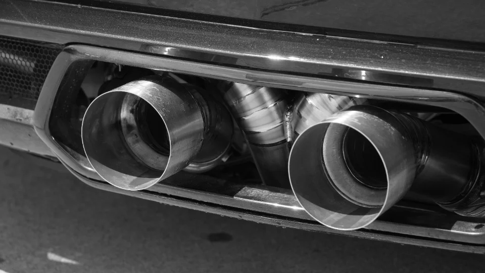 Close-up of a performance car's dual stainless steel exhaust tips and custom piping.