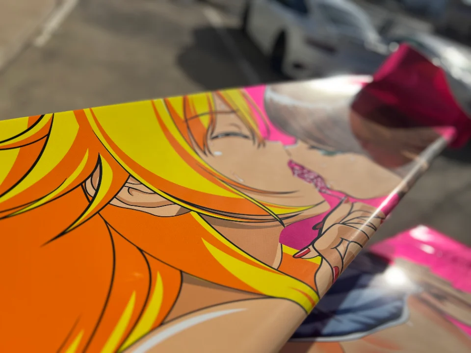Close-up of a custom anime-style car wrap featuring two women kissing, applied to a vehicle's exterior.