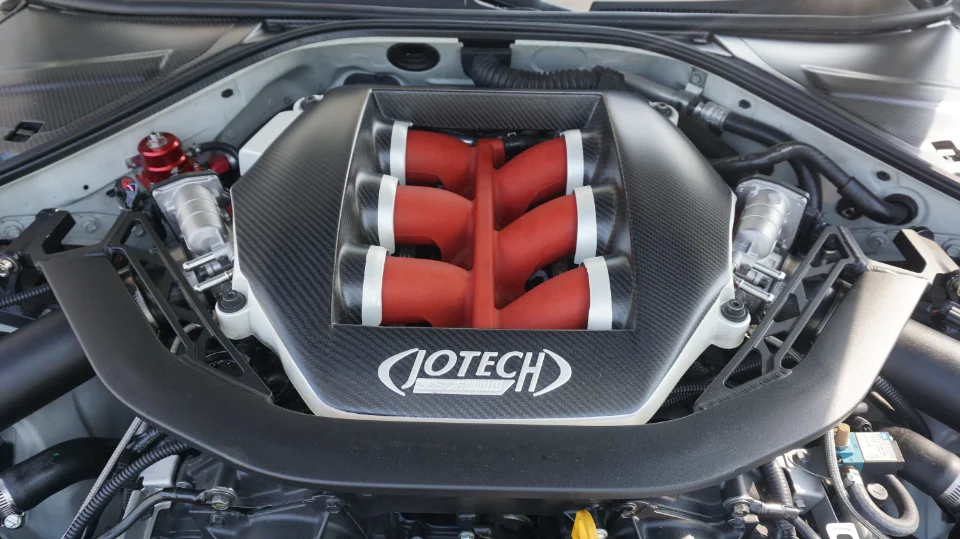 Close-up of a Jotech tuned Nissan GT-R engine bay featuring a carbon fiber intake manifold and red fuel pressure regulator.