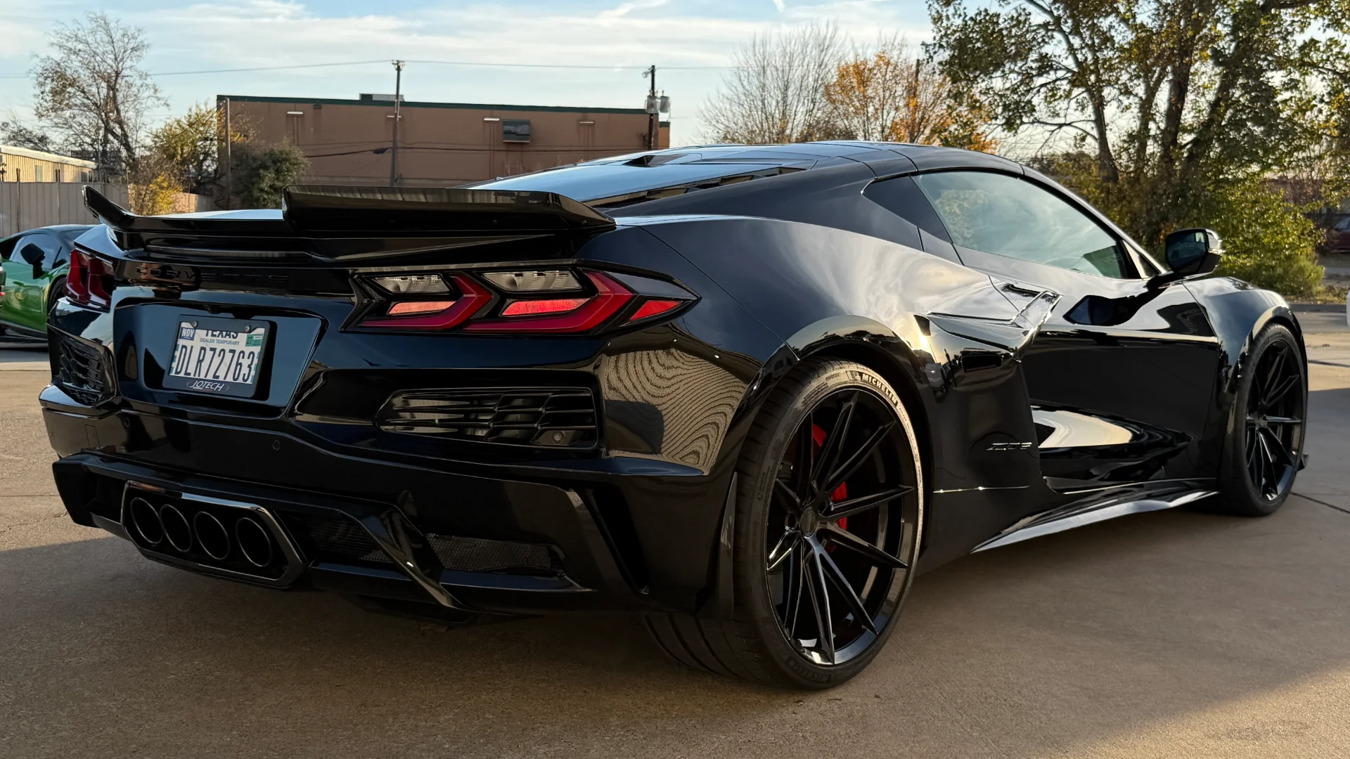 A sleek black Chevrolet Corvette C8.R with aftermarket wheels and a rear spoiler, parked outdoors.