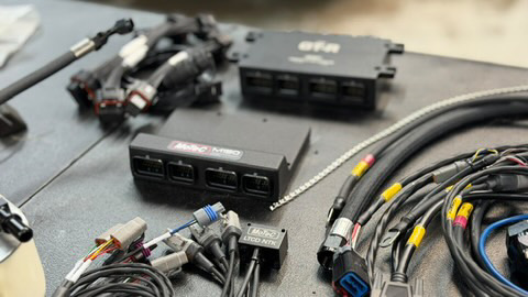 MoTeC M180 ECU and custom wiring harness for a high-performance vehicle build, laid out on a workbench.