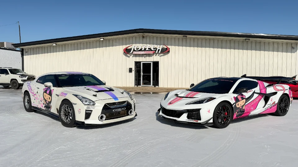 Two custom-wrapped performance cars, a Nissan GT-R and a Corvette C8, parked outside the Jotech Motorsports facility.
