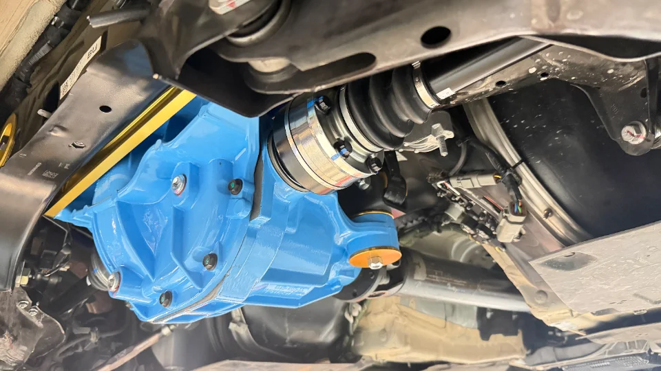 Close-up view of a custom blue differential and drivetrain components installed on the underside of a performance car.