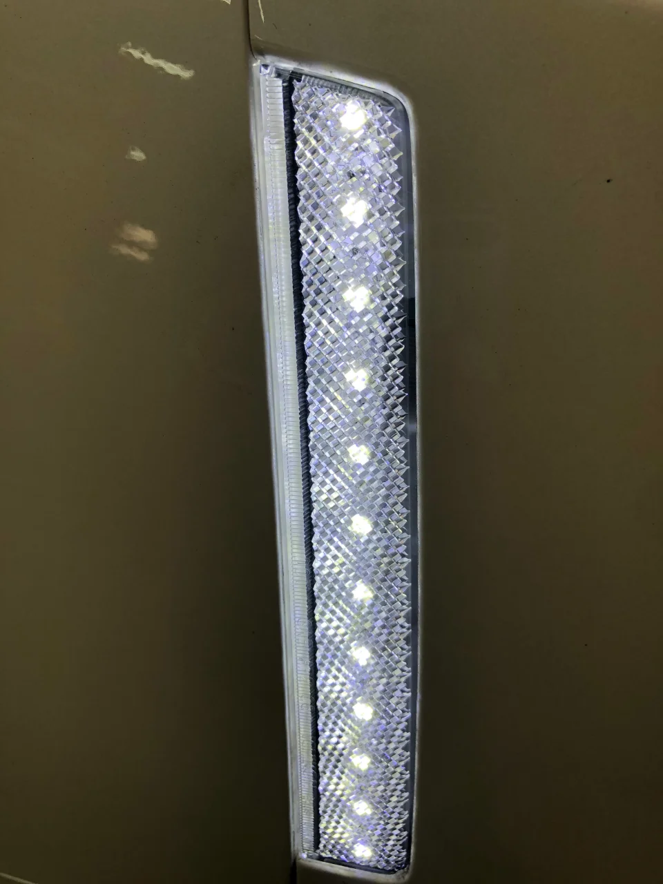 Close-up of an aftermarket LED side marker light on a car's body panel, showing individual bright LEDs.