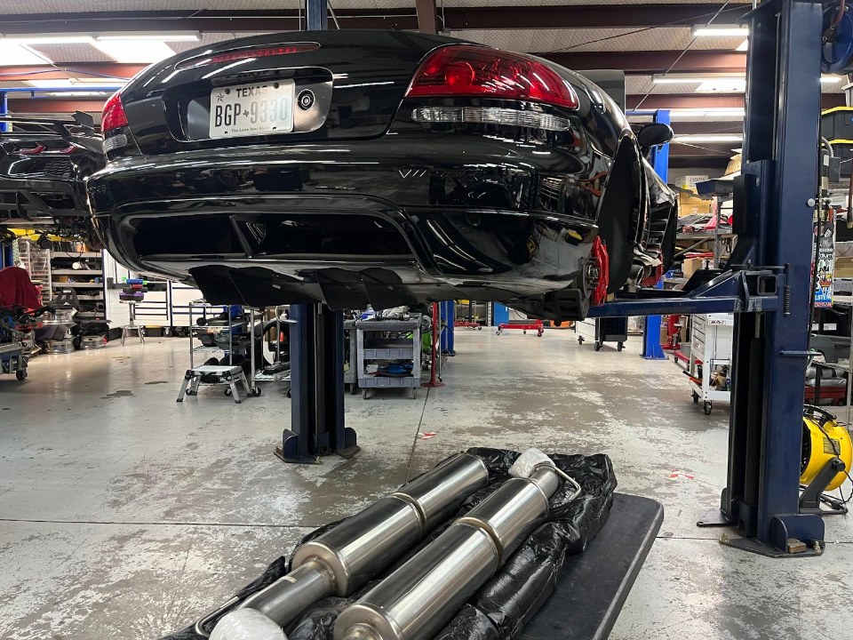 Black Dodge Viper on a lift in a performance shop with new exhaust components ready for installation.