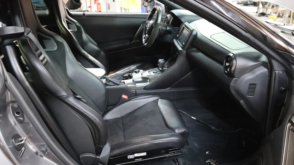 Detailed view of a Nissan GT-R interior featuring Recaro seats, steering wheel, and carbon fiber trim on the center console.