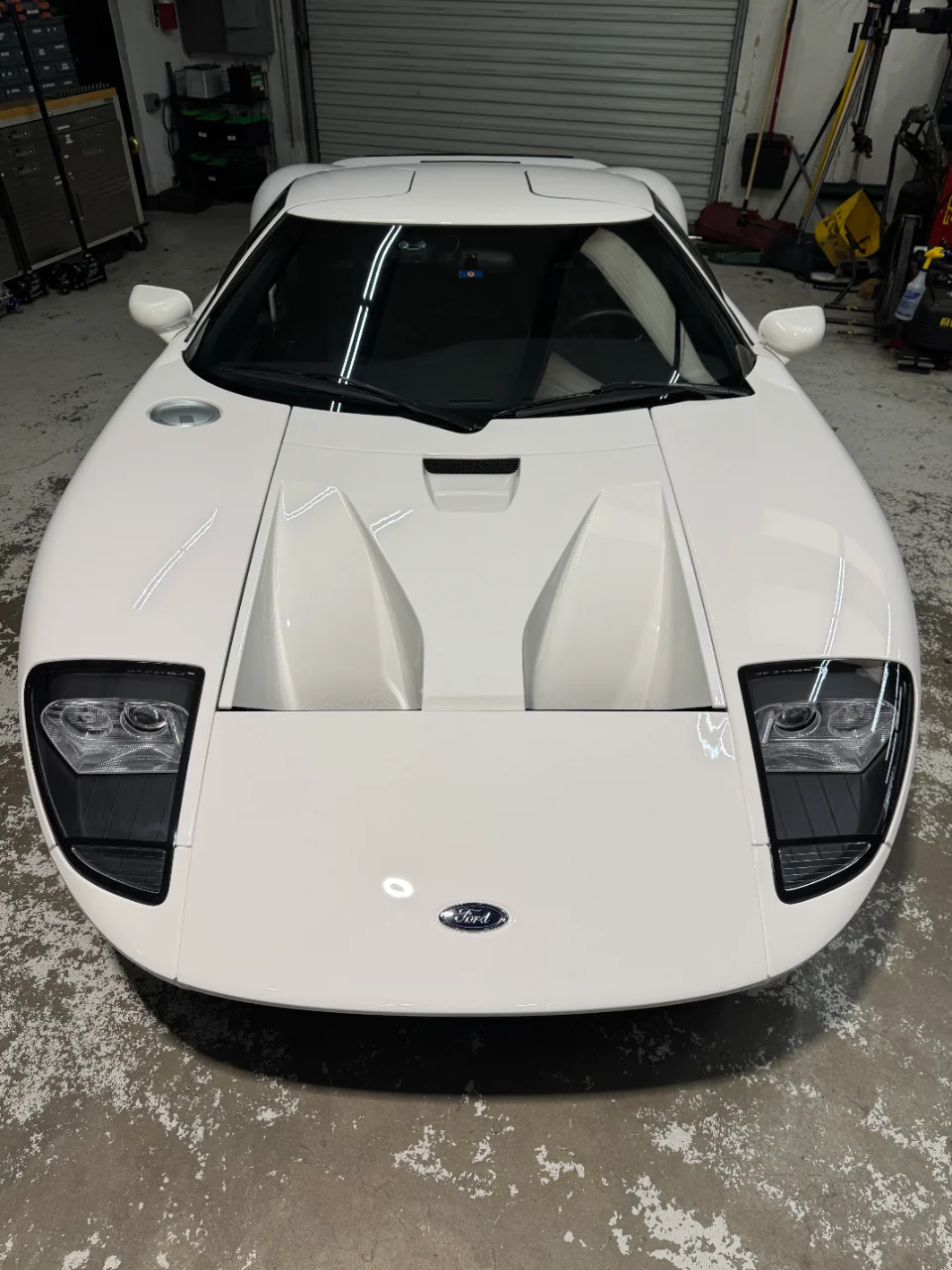 A pristine white Ford GT supercar parked in a garage, viewed from the front.