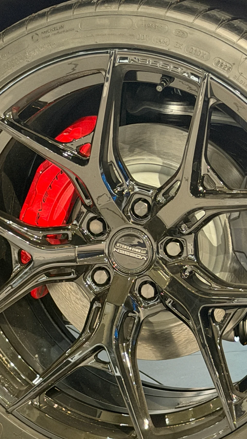 Close-up of a black Vossen wheel with red Corvette brake calipers and Michelin tire, showcasing the intricate design.