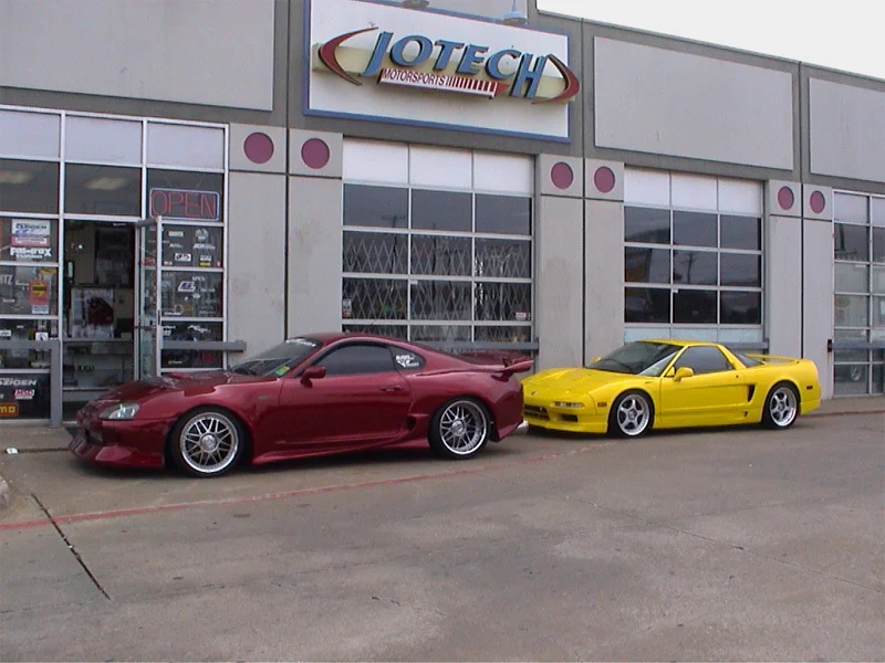 A red Toyota Supra and a yellow Acura NSX parked outside Jotech Motorsports performance tuning shop.