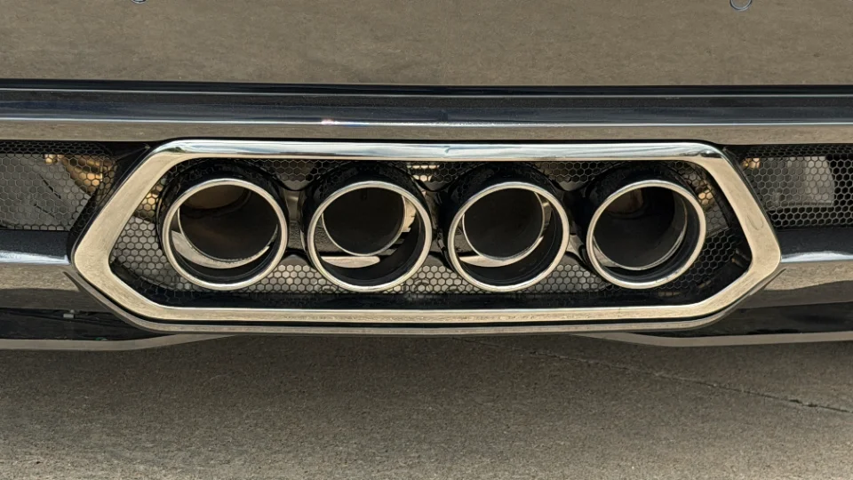 A close-up of chrome quad exhaust tips integrated into the rear bumper of a performance car.