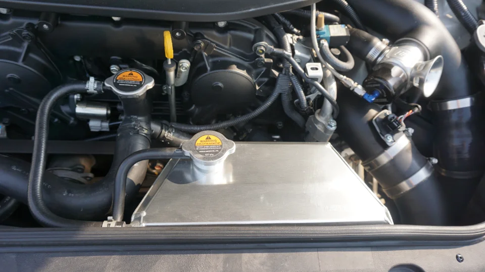 Close-up of a modified car engine bay featuring an aftermarket aluminum radiator and a blow-off valve.