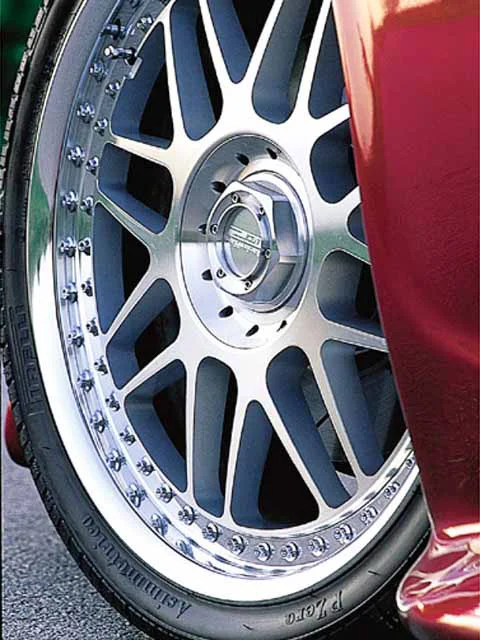A close-up of a multi-spoke silver wheel with a Pirelli P Zero tire on a red car.