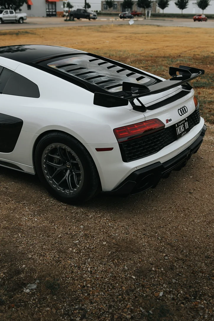Rear view of a white Audi R8 with an aftermarket carbon fiber wing, custom wheels, and an aggressive rear diffuser.