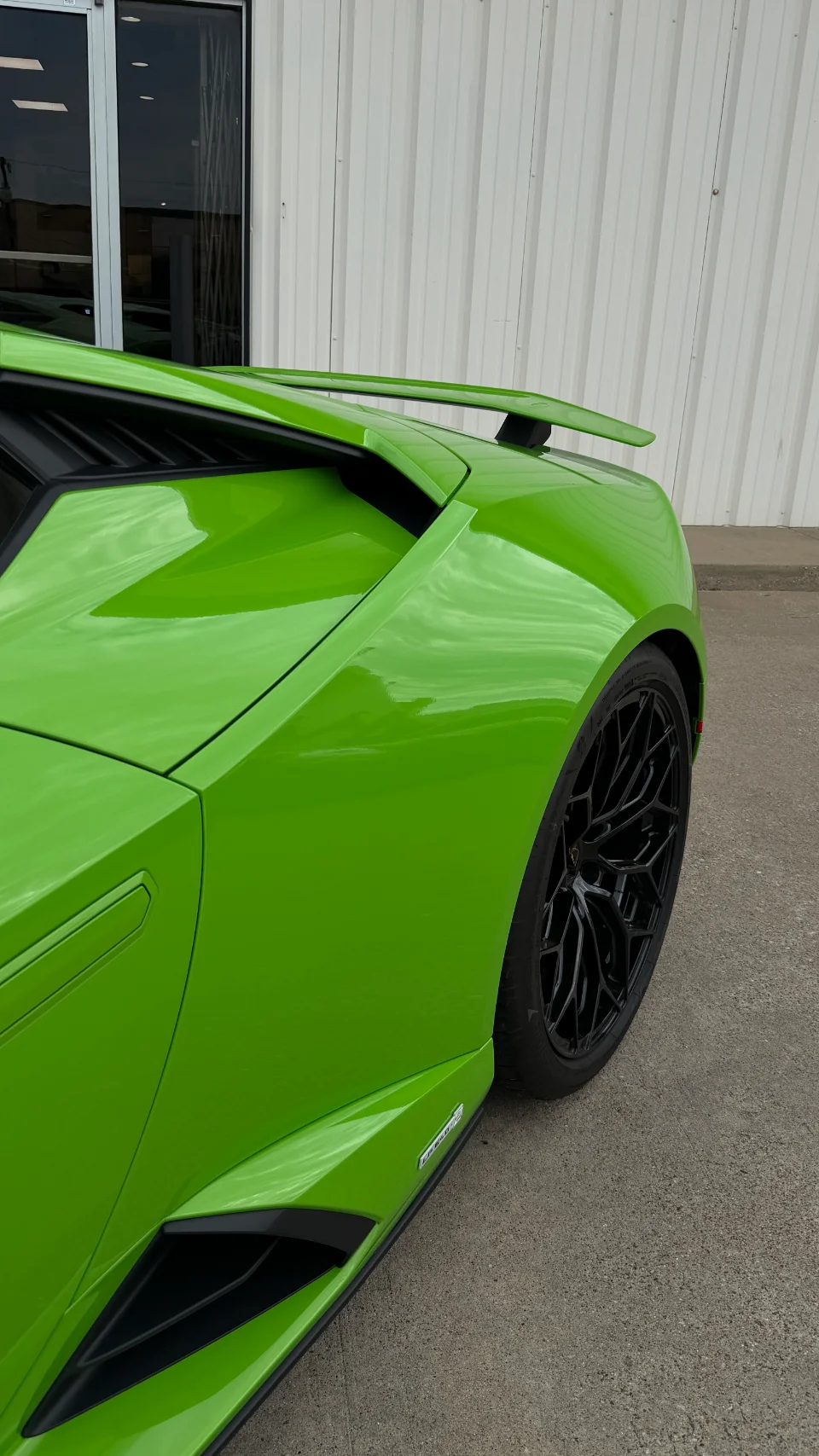 Close-up detail of a bright green Lamborghini Huracan's rear wheel, black multi-spoke rim, and side aero.
