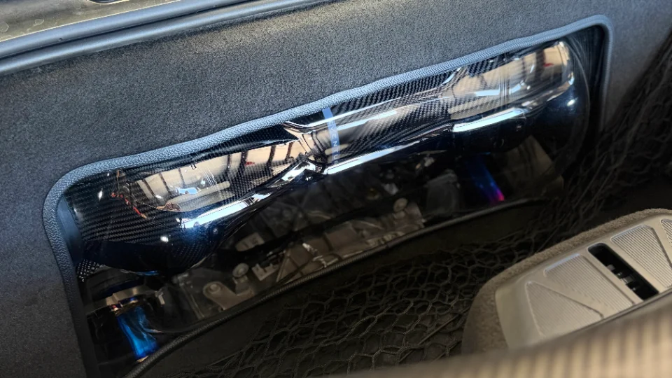 Close-up detail of a carbon fiber intake system in a supercar engine bay, featuring an Aventus intake.