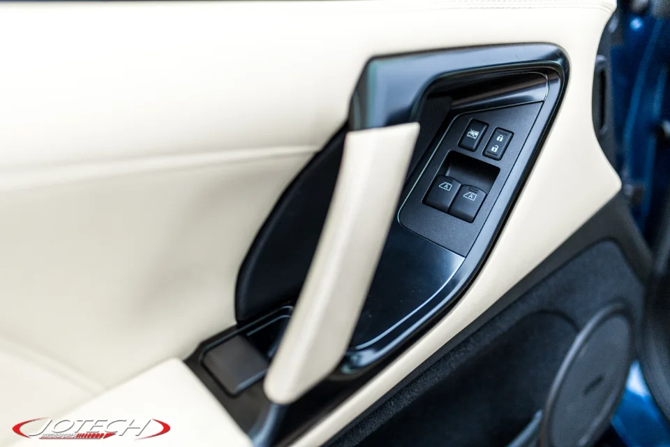 Close-up of a car's interior door panel with beige leather trim and black window and lock controls.