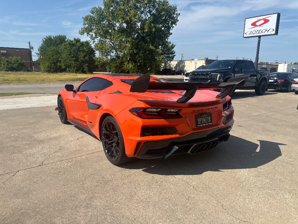 Orange Chevrolet Corvette C8.R with an aftermarket rear wing and black wheels, parked outside Jotech Motorsports.