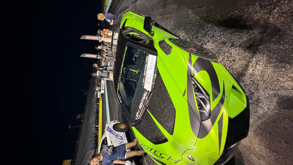 A lime green Lamborghini Huracan with black livery in the staging lanes at a night drag racing event.