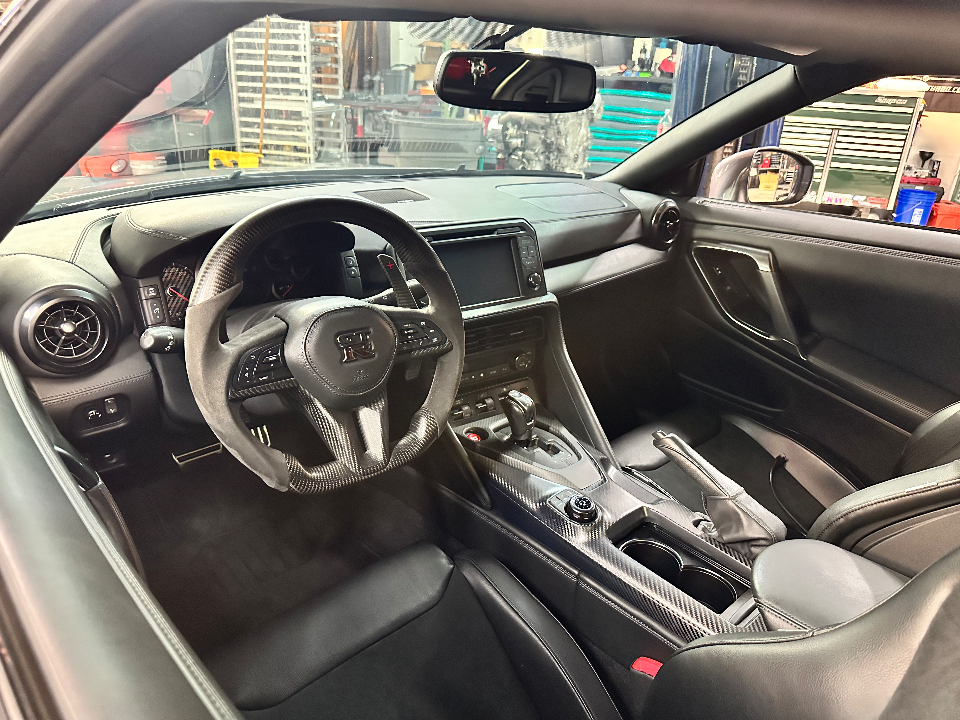 Detailed view of a Nissan GT-R interior, featuring a carbon fiber steering wheel, dashboard, and center console.