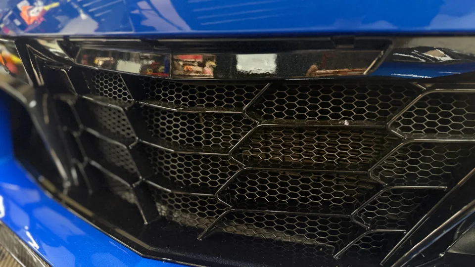 Close-up of the honeycomb front grille on a blue C8 Corvette.