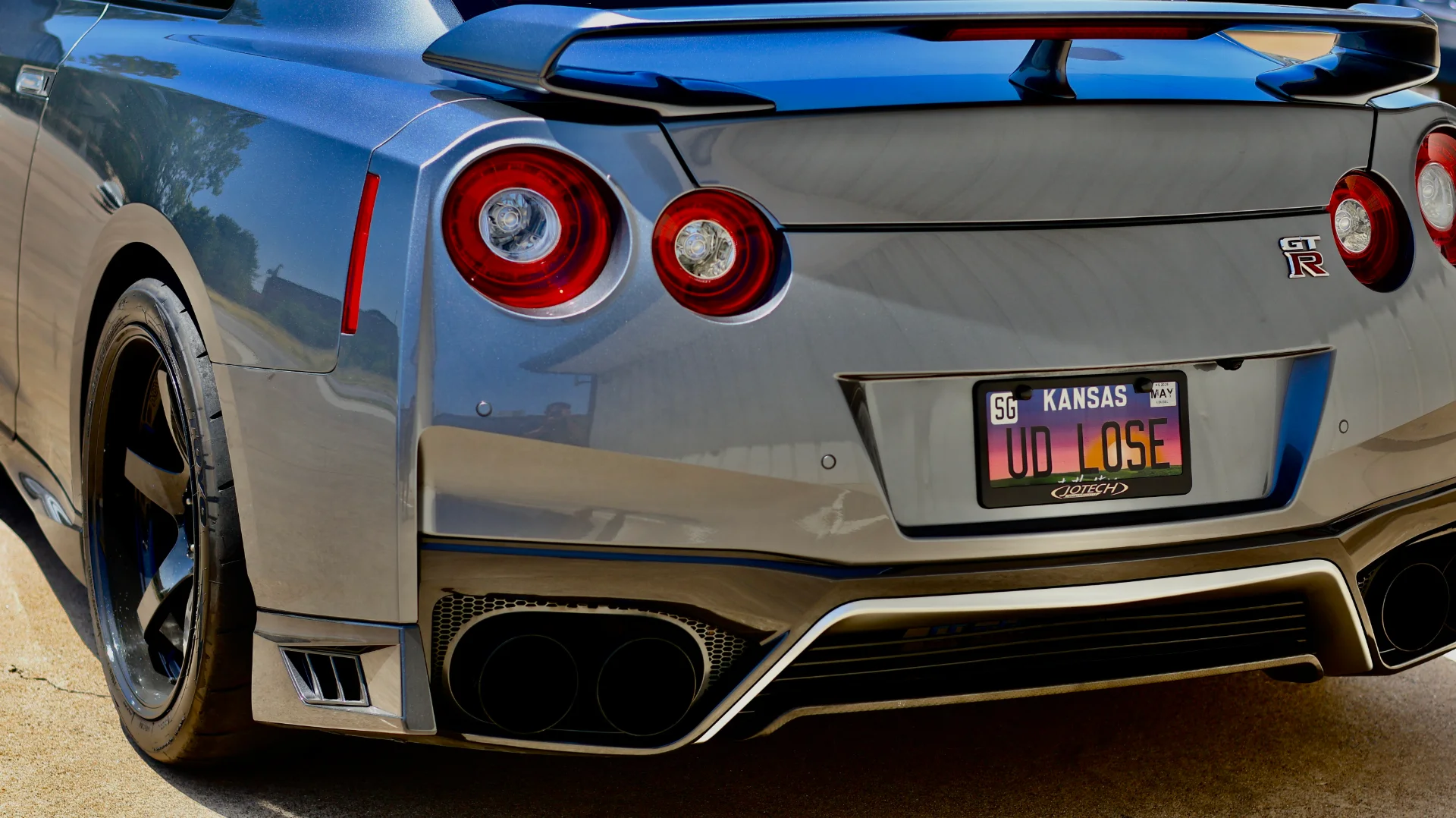 Rear view of a grey Nissan GT-R R35 showcasing its custom license plate, quad exhaust tips, and diffuser.
