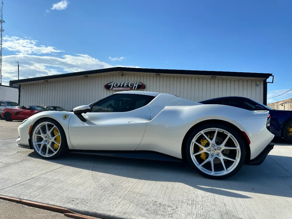 A white Ferrari with custom silver wheels and yellow brake calipers parked outside Jotech Motorsports.