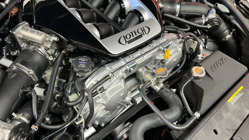 A close-up view of a Jotech-tuned Nissan GT-R engine bay, showcasing the custom intake manifold and Alpha Performance components.