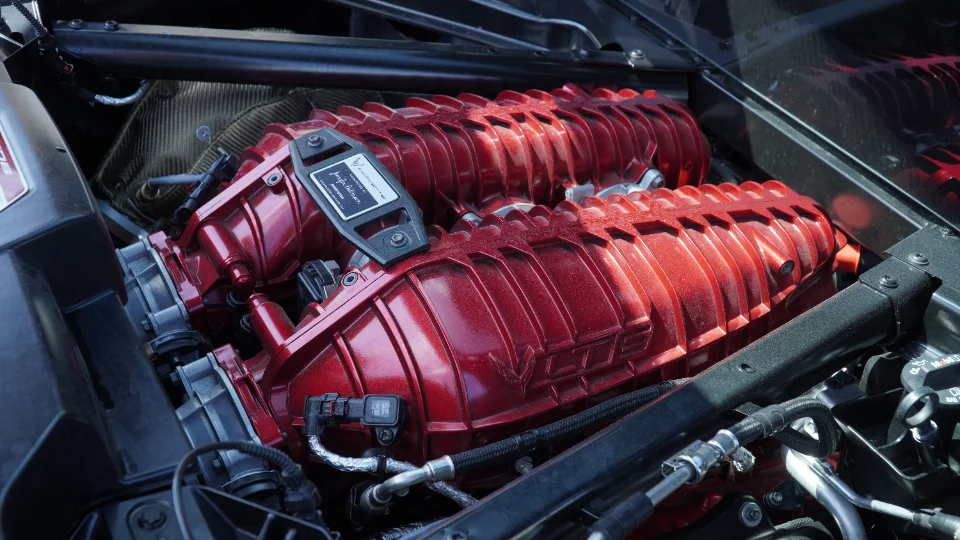 Close-up of a red aftermarket supercharger in the engine bay of a C8 Corvette.