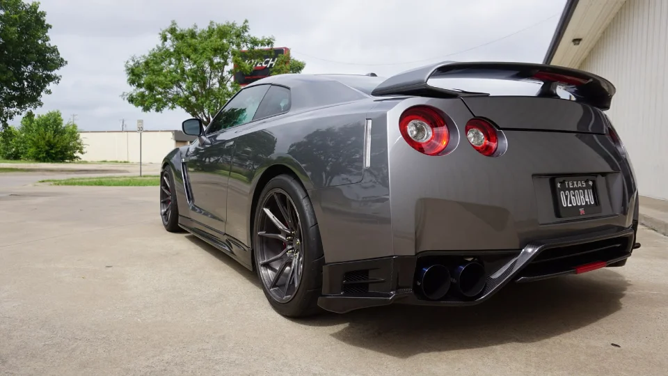 Rear view of a grey Nissan GT-R with aftermarket wheels, exhaust, and carbon fiber aero parked outside Jotech Motorsports.