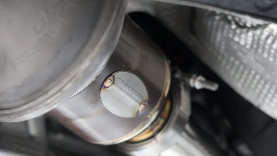 A close-up of a Farspeed Motorsport stainless steel exhaust system with visible welds and heat shielding.