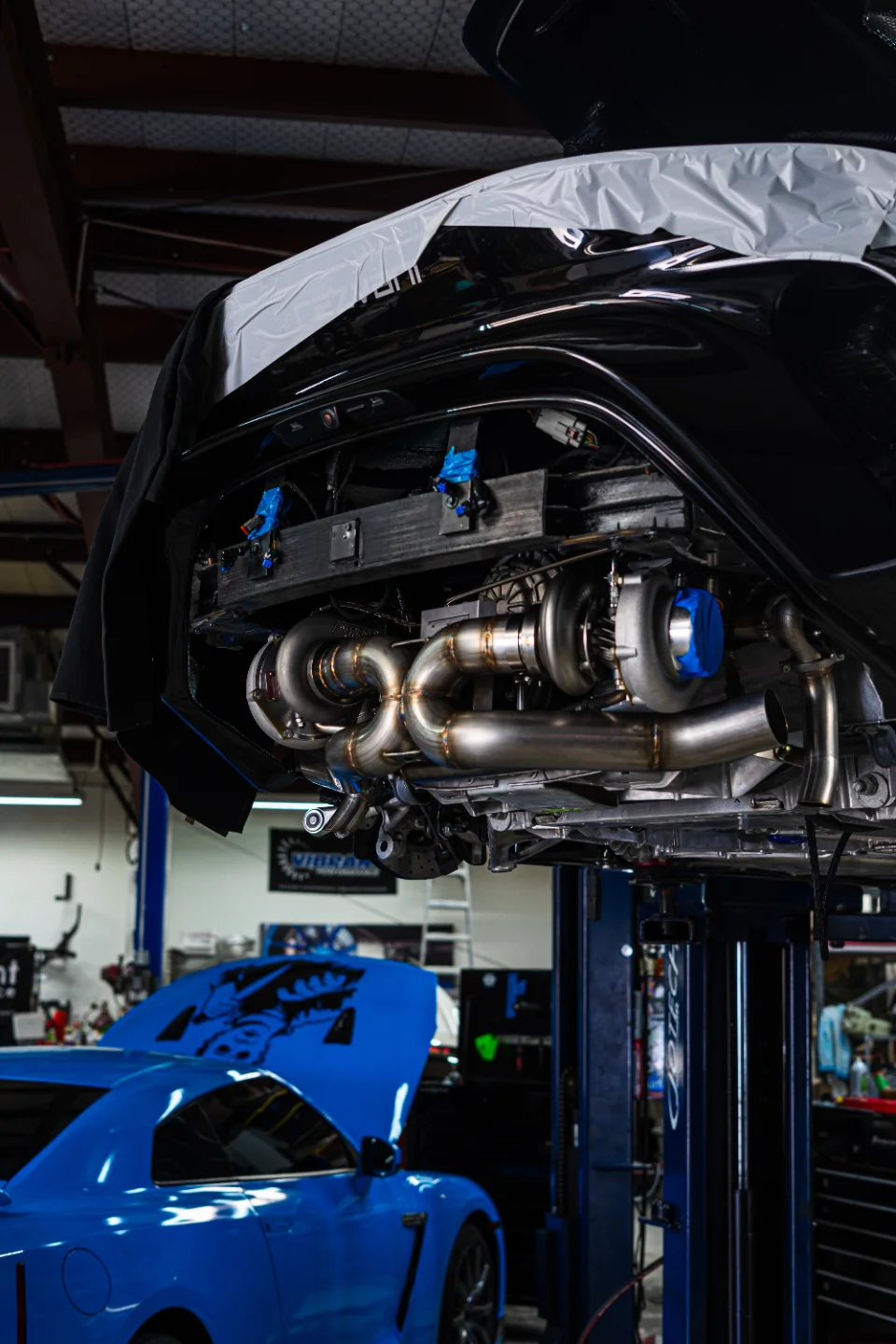 A Nissan GT-R on a lift in a shop, showcasing a custom twin-turbo and exhaust system installation.