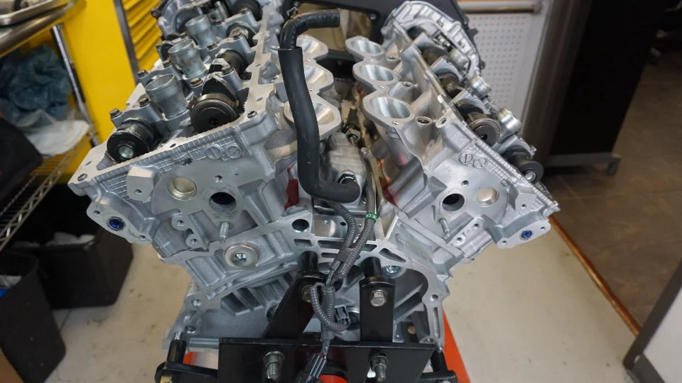 A close-up view of a V8 engine block with cylinder heads and camshafts being assembled in a performance shop.