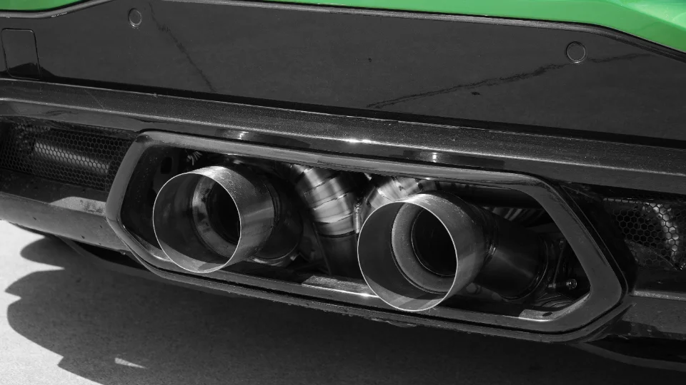 Close-up of a performance car's quad exhaust tips integrated into the rear bumper.
