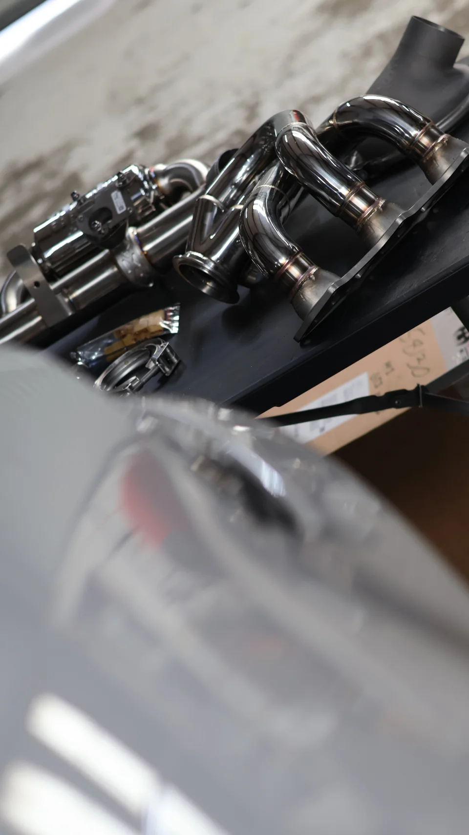 Polished stainless steel performance exhaust headers and downpipes, displayed as a product for high-performance vehicles.