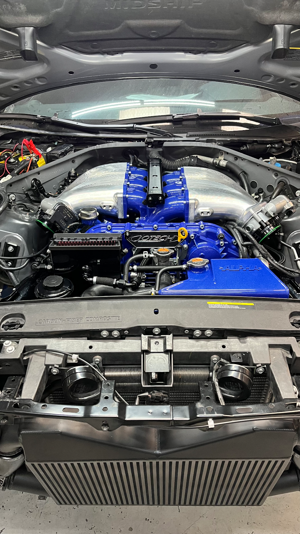 A detailed view of a Jotech-tuned Nissan GT-R engine bay featuring a custom blue intake manifold and large intercooler.