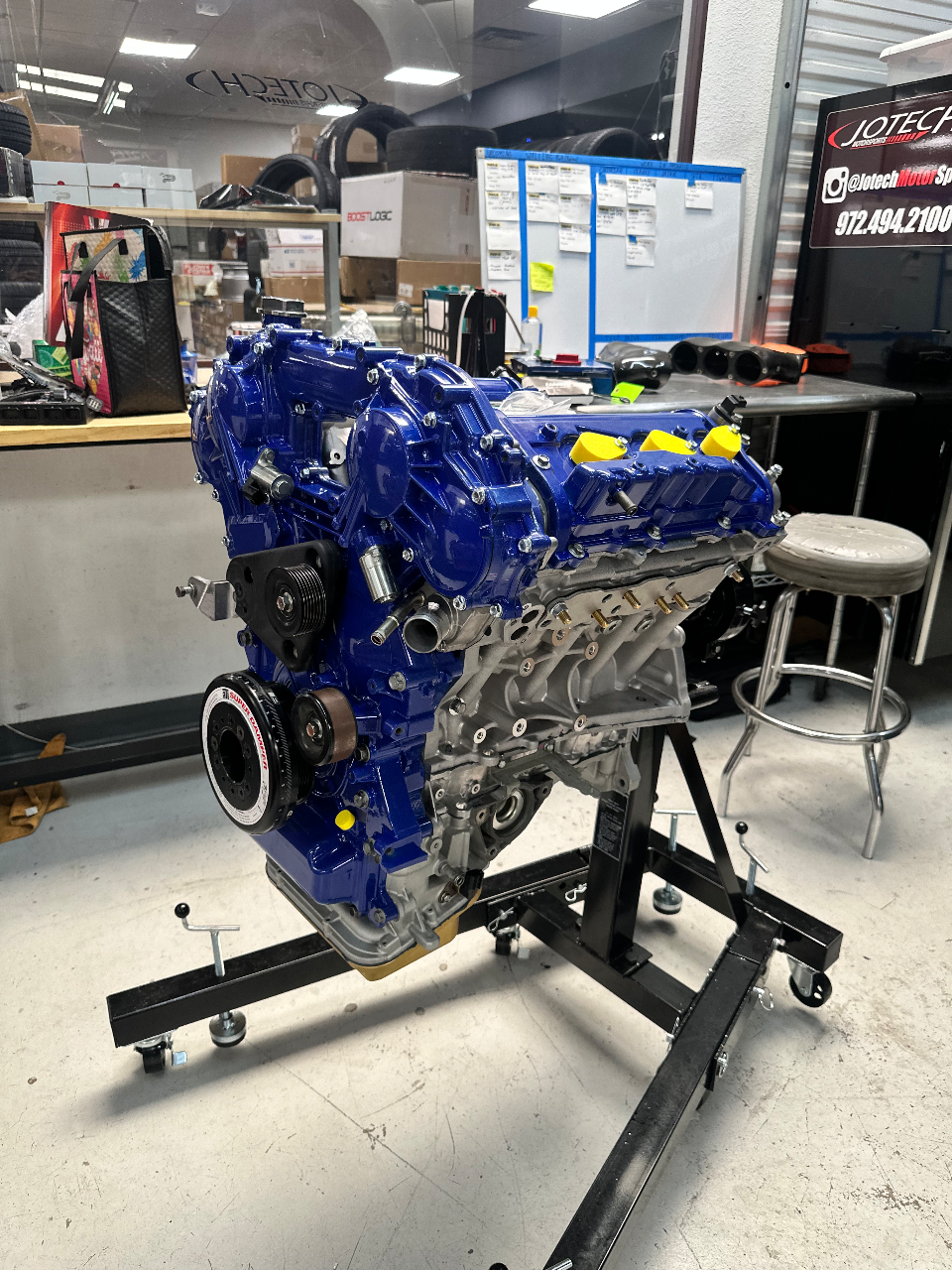 A blue built engine on an engine stand in the Jotech Motorsports shop.