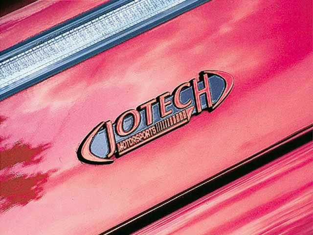 Close-up of a Jotech Motorsports emblem on the red trunk lid of a car.