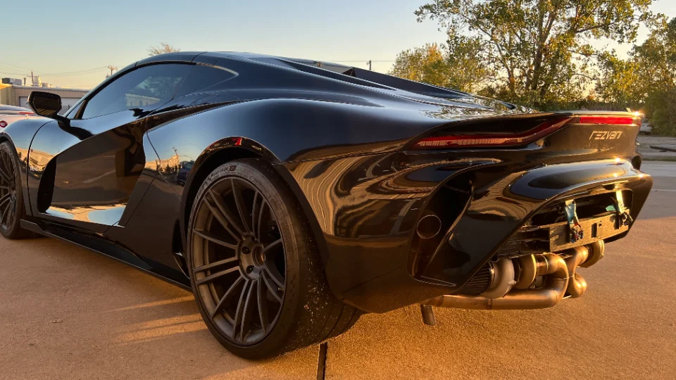 Rear view of a black Rezvani supercar showcasing its exposed turbo and exhaust system.