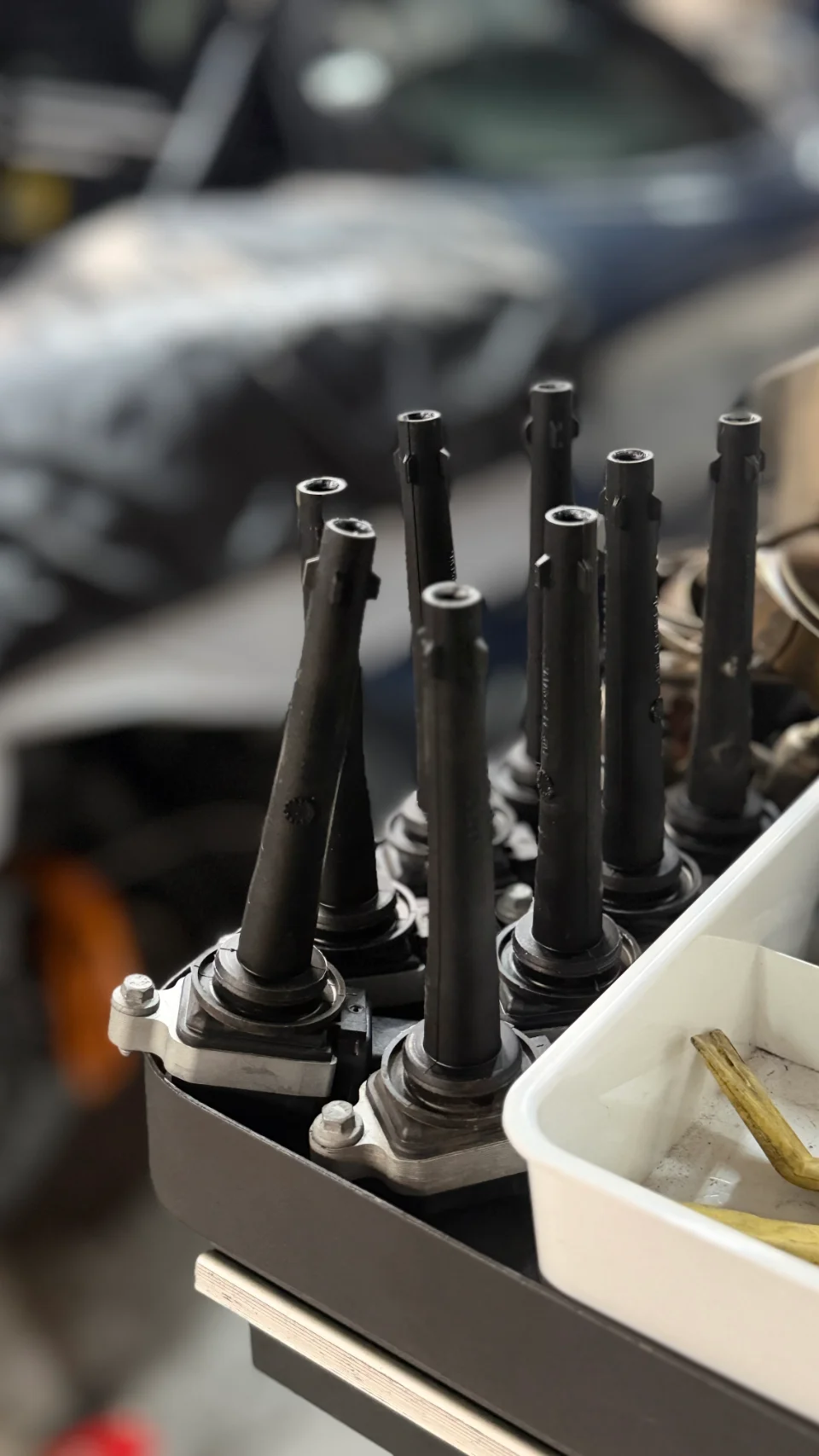 Close-up of multiple performance ignition coils in a tray at a tuning shop.