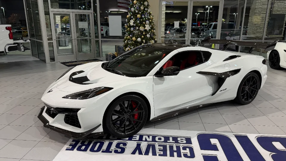 White Chevrolet Corvette C8 Z06 displayed in a dealership showroom with a Christmas tree in the background.